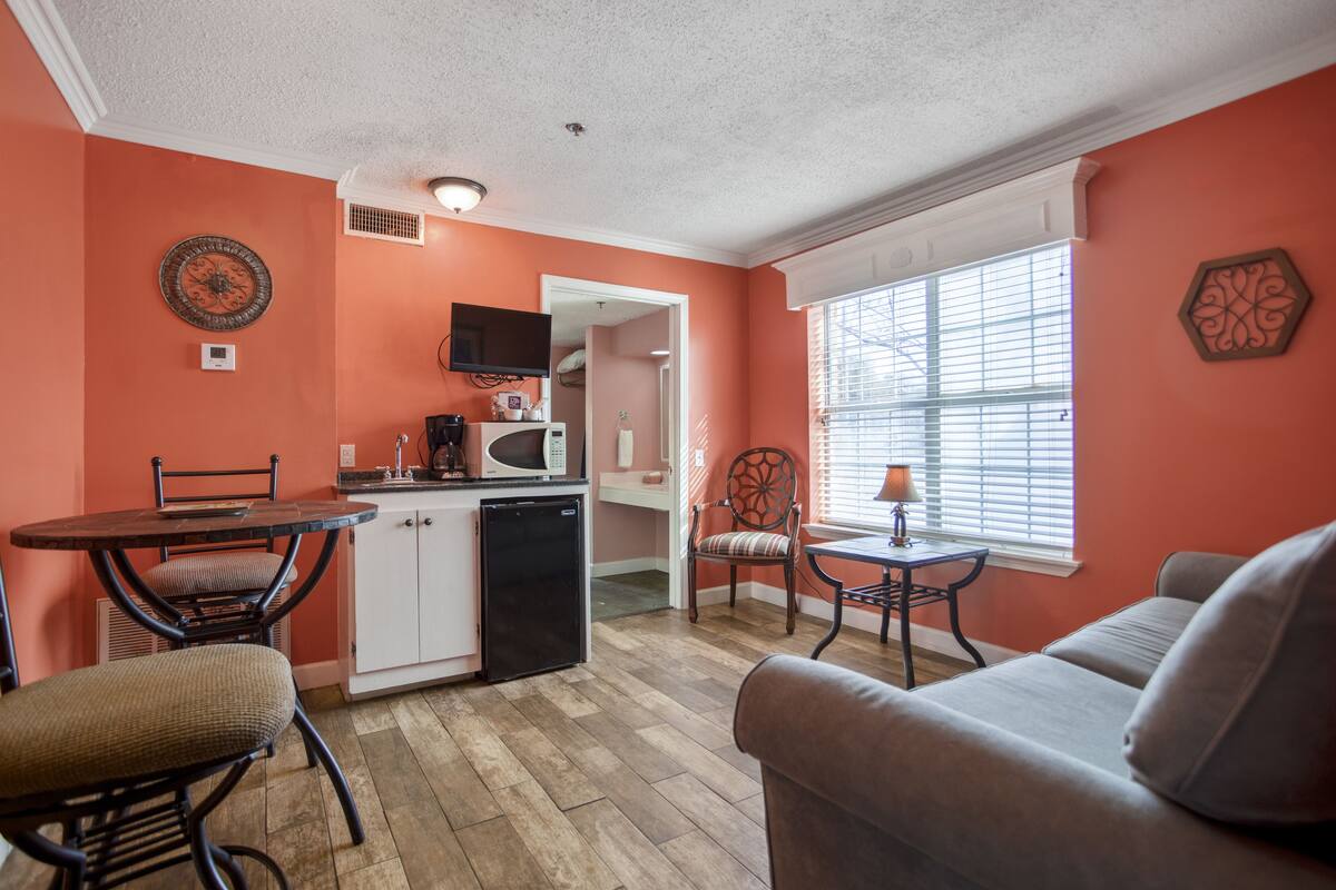 A compact living space with a kitchenette, a dining area, and a seating area with a window providing natural light.