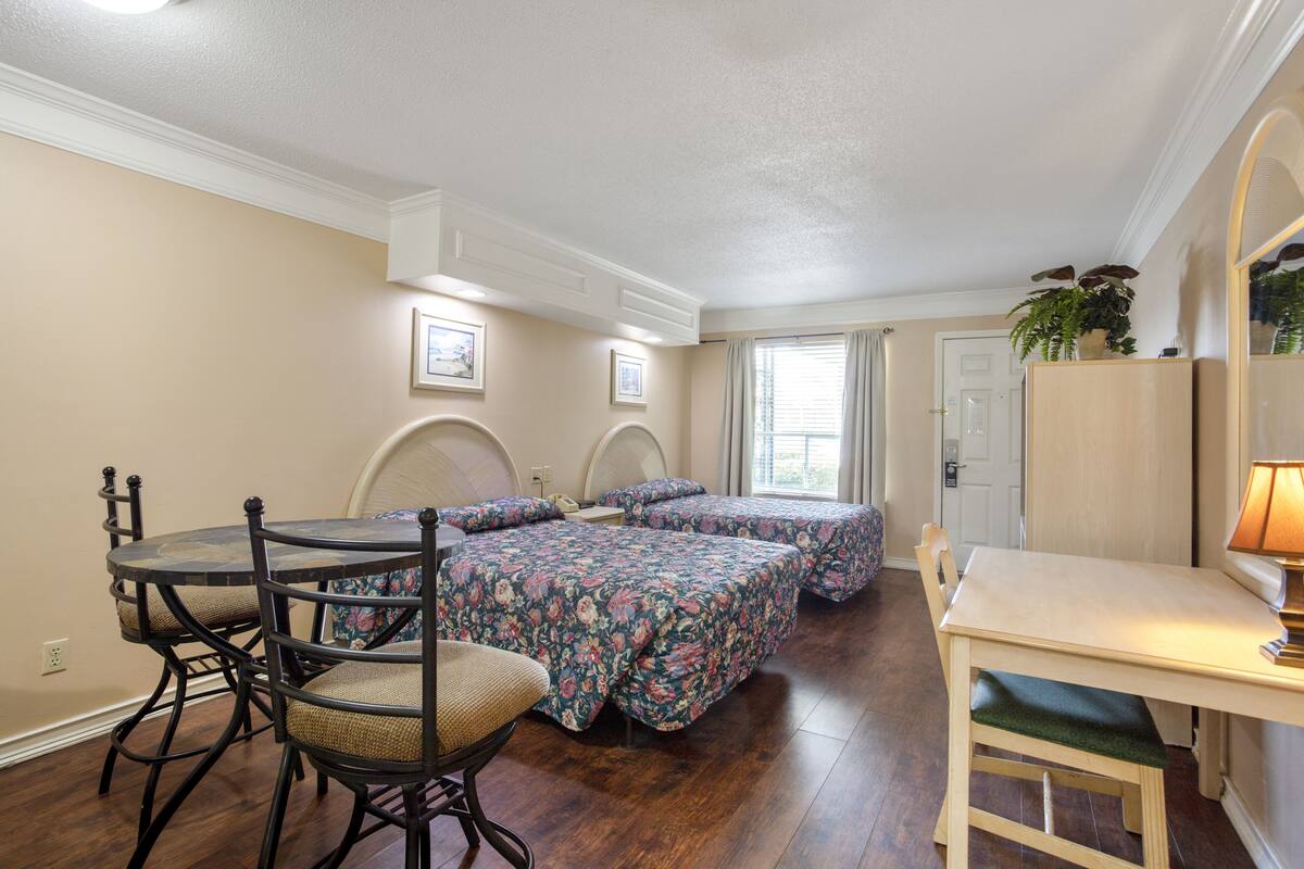 A bedroom with two beds, a wooden table, and a chair.