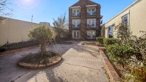 A multi-story residential building with balconies, a brick pathway, and surrounding greenery. - Edgewater Inn (Biloxi)