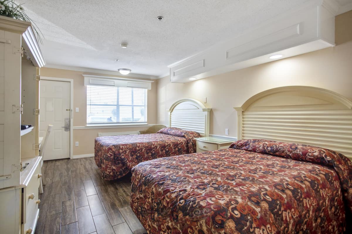 A bedroom with two beds, a dresser, a window with blinds, and a ceiling fan.