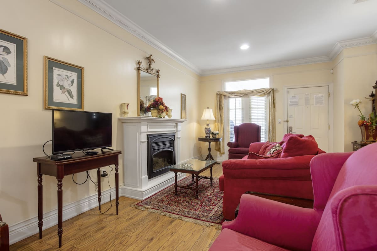 A living room with a fireplace, a television on a wooden table, and red sofas.