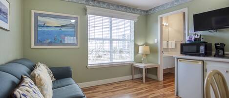 A compact living space with a sofa, a small table, a microwave, and a television.