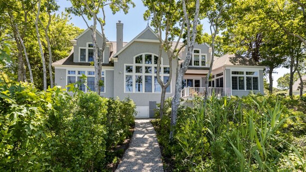 A large, two-story house with a covered porch and a gravel pathway leading to the entrance. - Beautiful New Seabury Home in Mashpee (Mashpee)