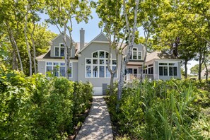 A large, two-story house with a covered porch and a gravel pathway leading to the entrance. - Beautiful New Seabury Home in Mashpee (Mashpee)