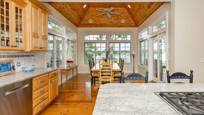A spacious kitchen with wooden cabinets, a granite countertop, and a dining area with a table and chairs. - Beautiful New Seabury Home in Mashpee (Mashpee)