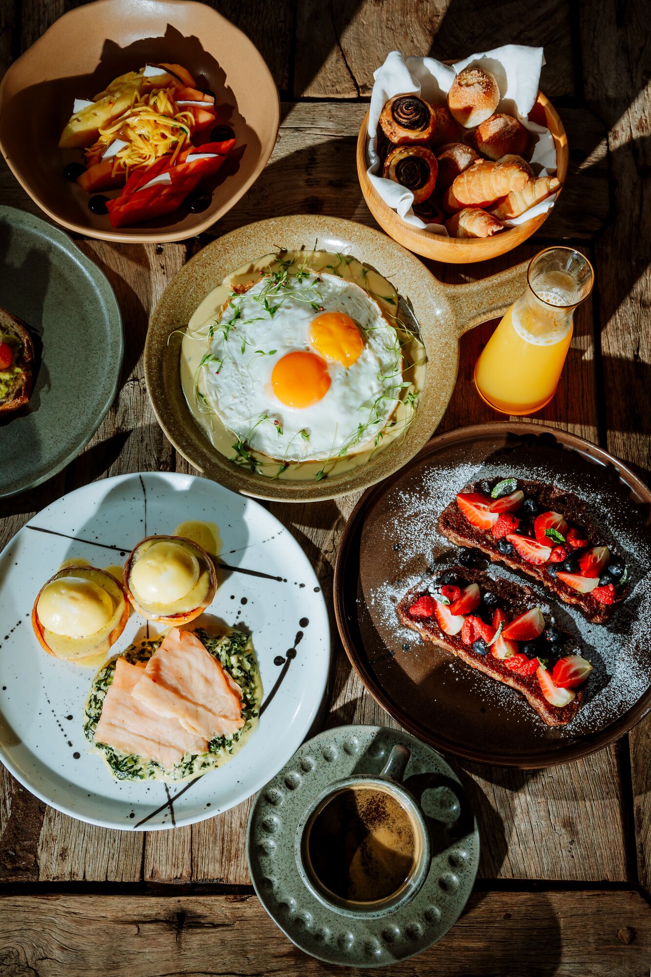 Un desayuno con diferentes opciones de comida, como huevos, salmón ahumado y tostadas con frutos rojos.