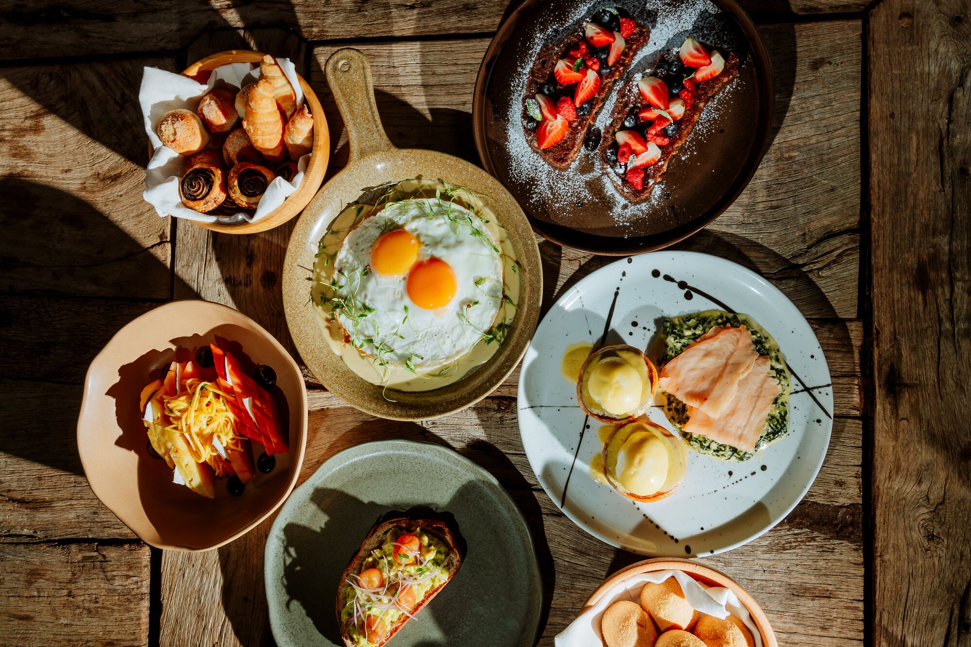 A variety of breakfast dishes on a wooden table.