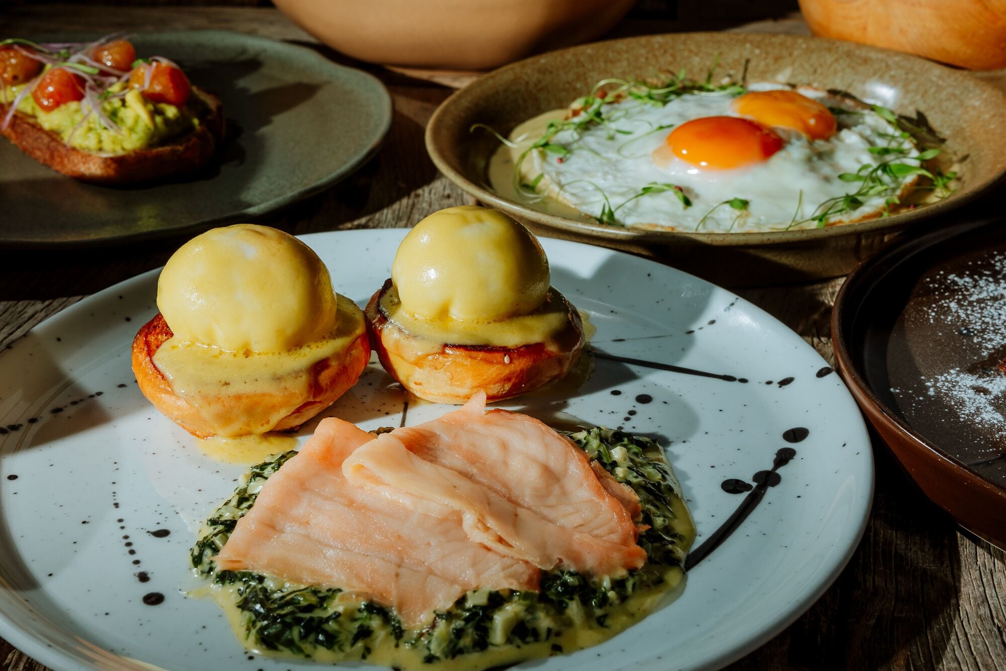 Diverse gerechten, waaronder eggs benedict, zalm en een bord met groenten.