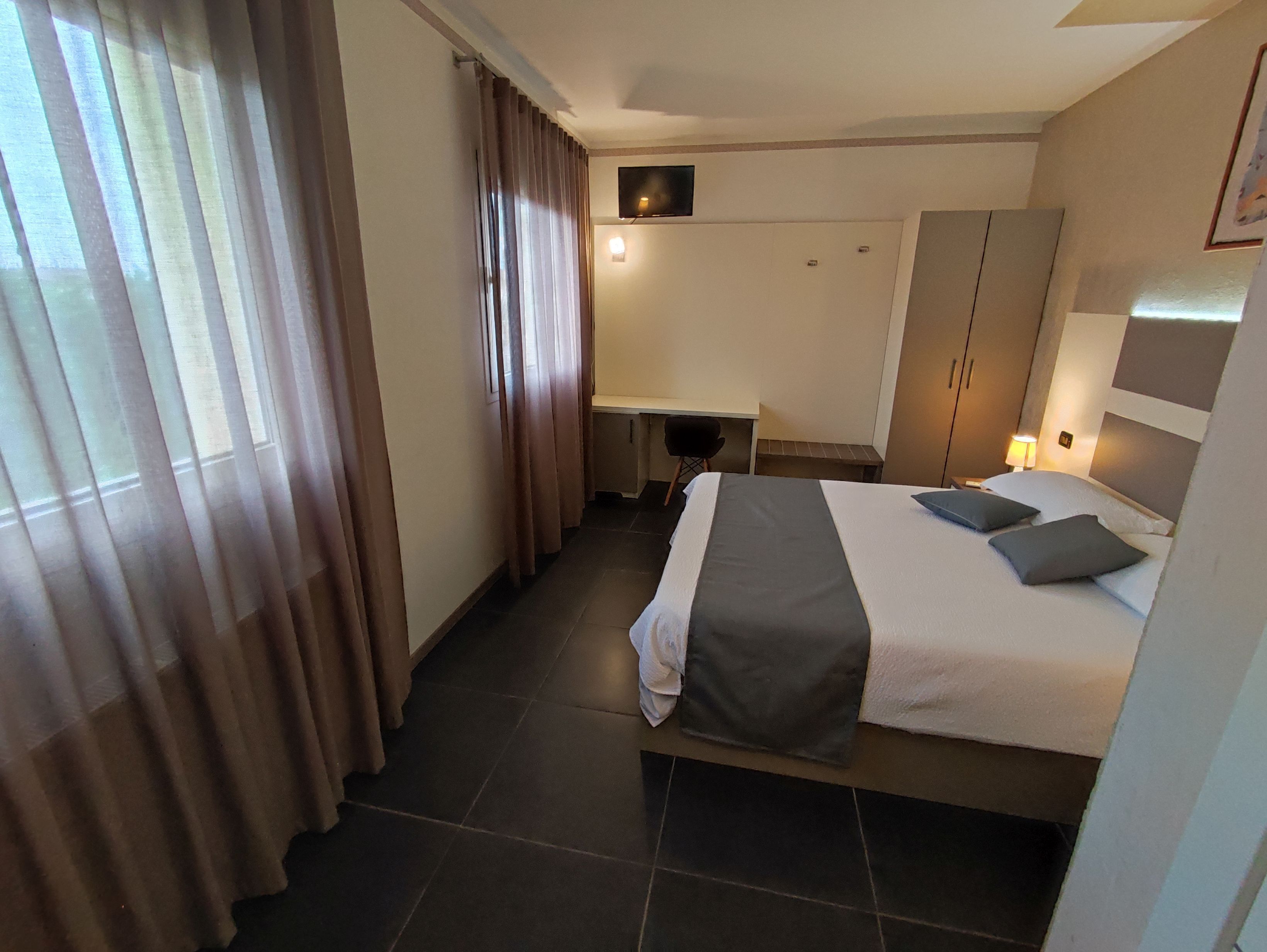 Une chambre d’hôtel avec un lit, un bureau et une chaise.