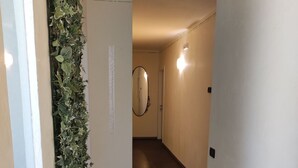 A hallway with a tiled floor, a wall-mounted mirror, and a vertical garden. - Therra Lodge (Preganziol)