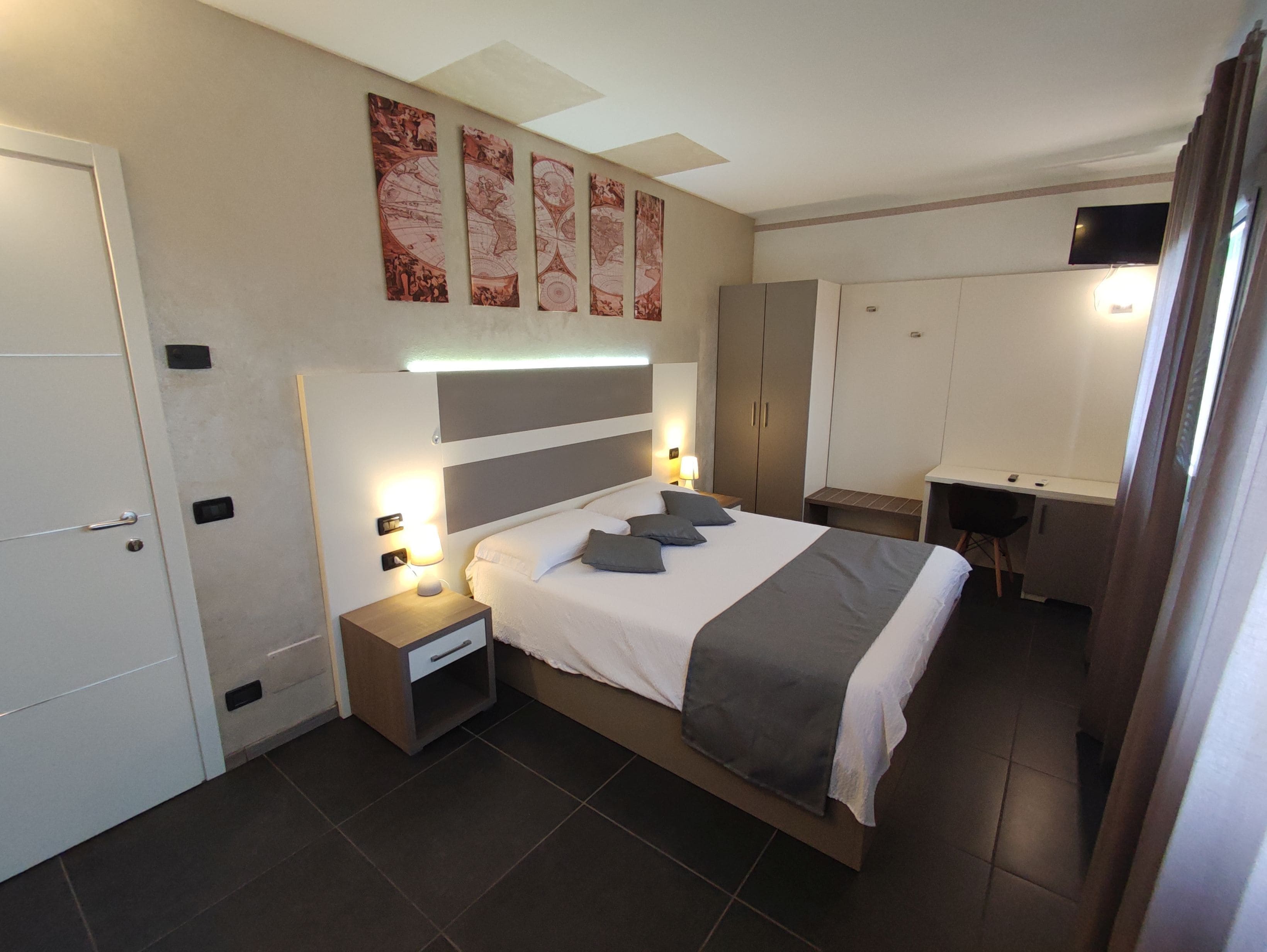 Une chambre d’hôtel moderne, dotée d’un grand lit, de tables de chevet, d’un bureau et d’une armoire.