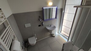 A modern bathroom with a toilet, bidet, sink, and a mirror with LED lights. - Therra Lodge (Preganziol)