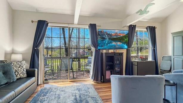A modern living room with a large TV, comfortable seating, and a view of the outdoors. - 237 Beautiful deck view, close to strip and Marina (Branson)