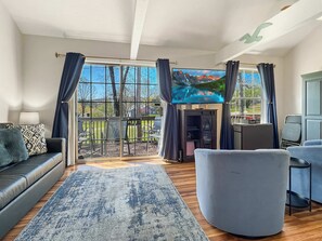A modern living room with a large TV, comfortable seating, and a view of the outdoors. - 237 Beautiful deck view, close to strip and Marina (Branson)