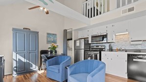 A modern kitchen with white cabinets, stainless steel appliances, and a dining area with blue chairs. - 237 Beautiful deck view, close to strip and Marina (Branson)