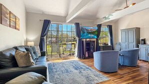 A spacious living room with a large window, a sofa, a blue armchair, and a wooden floor. - 237 Beautiful deck view, close to strip and Marina (Branson)