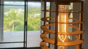 A hanging light fixture with a spiral design, a visible bulb, and a view of a balcony with greenery outside. - CASA TÚA, amazing views just minutes to the beach! (Puerto Escondido)