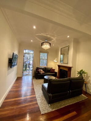 Cozy living room with a fireplace, comfortable sofa, and large window offering a view of the outside.
