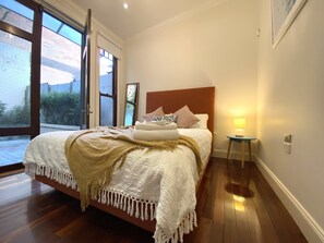 Cozy retreat with a large bed, wooden floor, and a bedside table with a lamp.