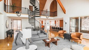 Ein geräumiger Wohnbereich mit moderner Treppe, einem Essbereich und einer durch eine offene Tür einsehbarer Küche.
