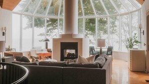Un salon spacieux doté d’une grande cheminée, de sièges confortables et d’un plafond haut laissant entrer la lumière naturelle.