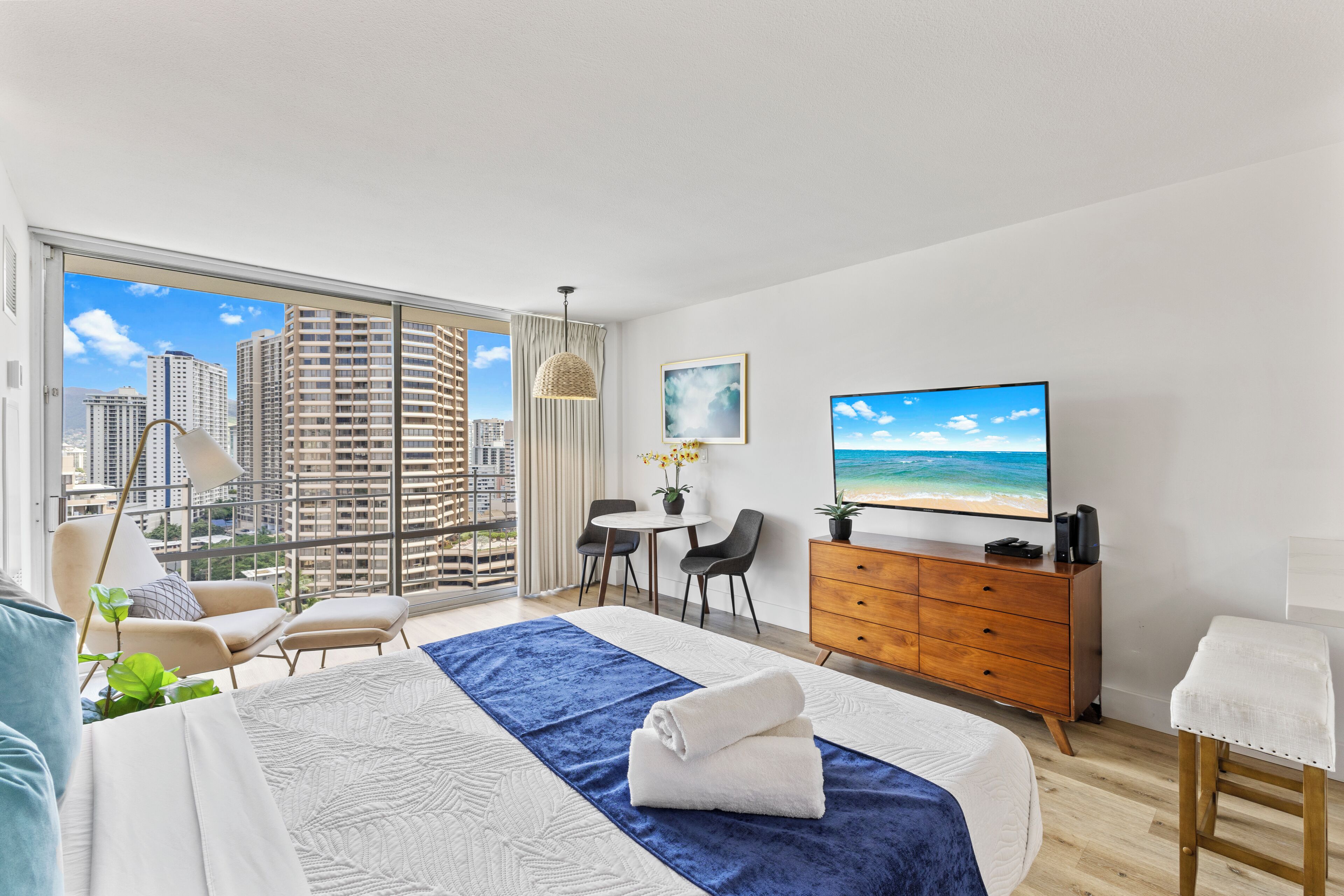 Habitación de hotel moderna con una cama grande, televisión, escritorio y vistas a la ciudad.