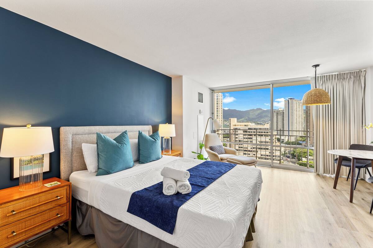 Quarto de hotel com uma cama grande, uma escrivaninha e vista para a paisagem urbana.