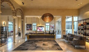 A spacious living area with a large rug, seating, artwork, and a television.