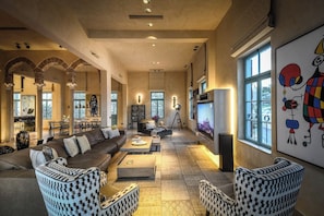 A spacious living room with a sofa, coffee table, and patterned chairs.