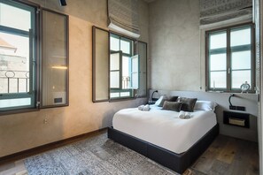 A bedroom with a large bed, two bedside tables, a nightstand, and a window with a view.