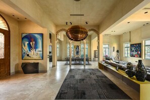 A spacious lobby with a central dining area, large artworks, and a modern chandelier.