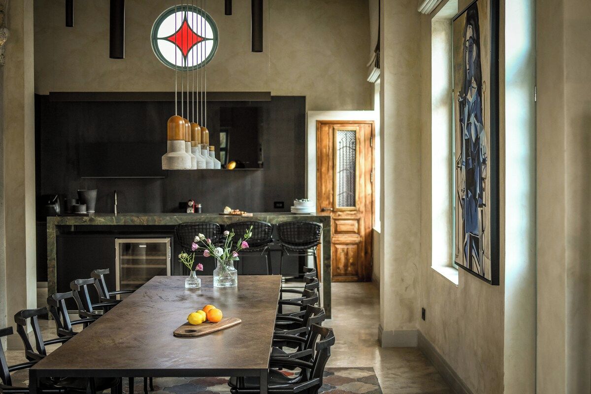 Een moderne keuken met een eethoek, met een groot schiereiland, hanglampen en een uitzicht op de aangrenzende eetkamer.