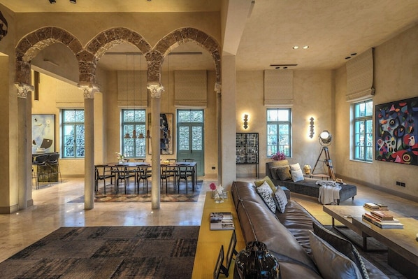 A spacious living area with a large sofa, a coffee table, and a dining area with chairs and a table.