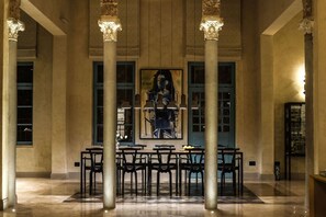 A lobby with a large painting, columns, and tables.