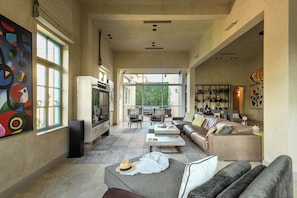 A spacious living room with a large window, a fireplace, and a modern sofa set.