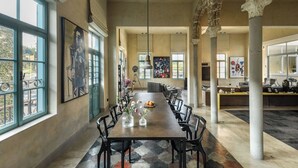 A spacious dining area with a long table, chairs, and artwork on the walls. - The Pearl of Jaffa: 3BR Luxury with Patio (Tel Aviv-Yafo)