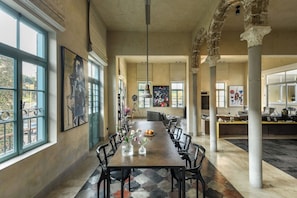 A spacious dining area with a long table, chairs, and artwork on the walls.