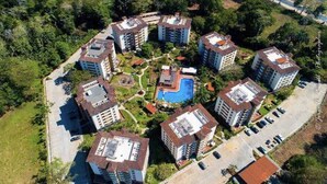 Ein Wohnkomplex mit mehreren Mehrfamilienhäusern, einem zentralen Schwimmbecken und umgebender Bepflanzung.
