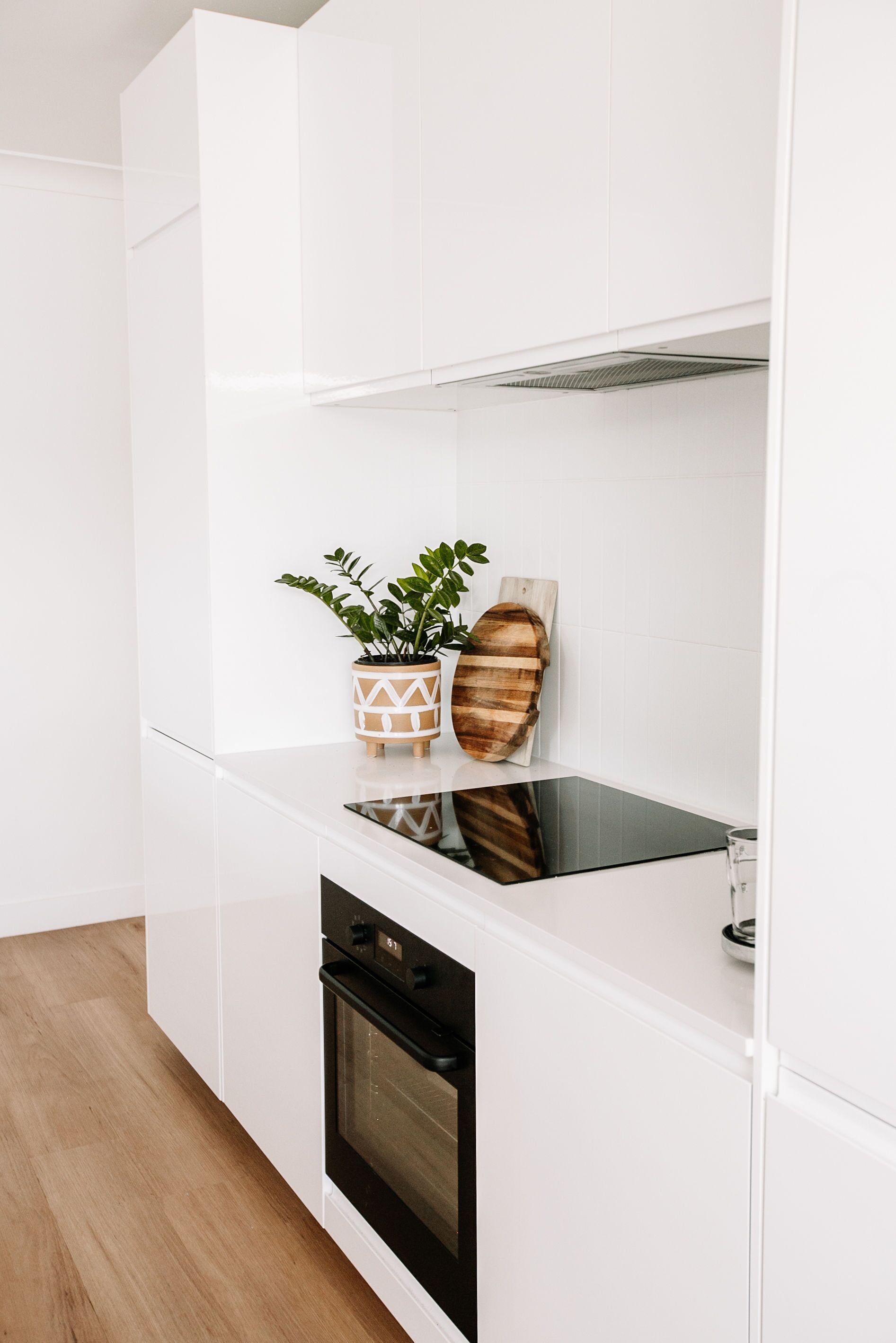 Een moderne keuken met witte kasten, een zwarte oven en een houten snijplank.