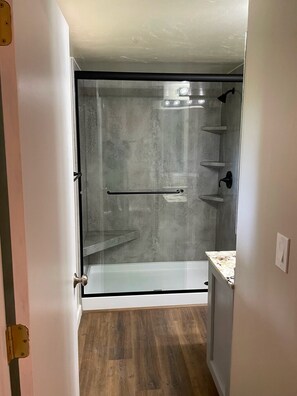 Une douche fermée par des parois en verre, dotée d’une poignée en métal et d’un porte-serviettes.