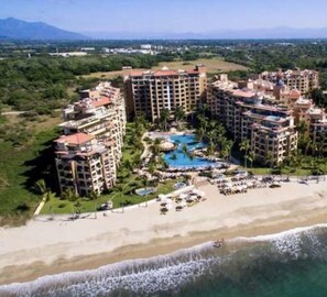 A resort with multiple high-rise buildings, a central pool area, and a beach.