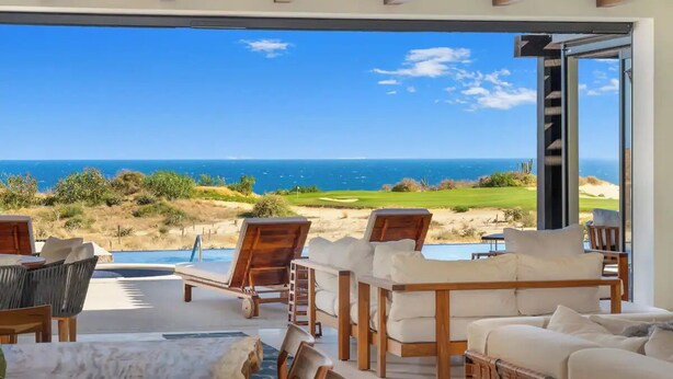 A modern outdoor seating area with a view of the ocean and a golf course.
