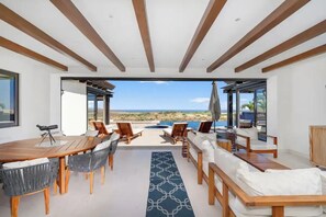 A modern outdoor dining area with a view of the beach and ocean. - Luxury Panoramic Ocean View Private Pool @Coronado (Cabo San Lucas)