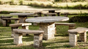 Outdoor stone picnic tables in a grassy area. - VILLA DAS PALMEIRAS Empório & Chalés (São Bento do Sapucaí)