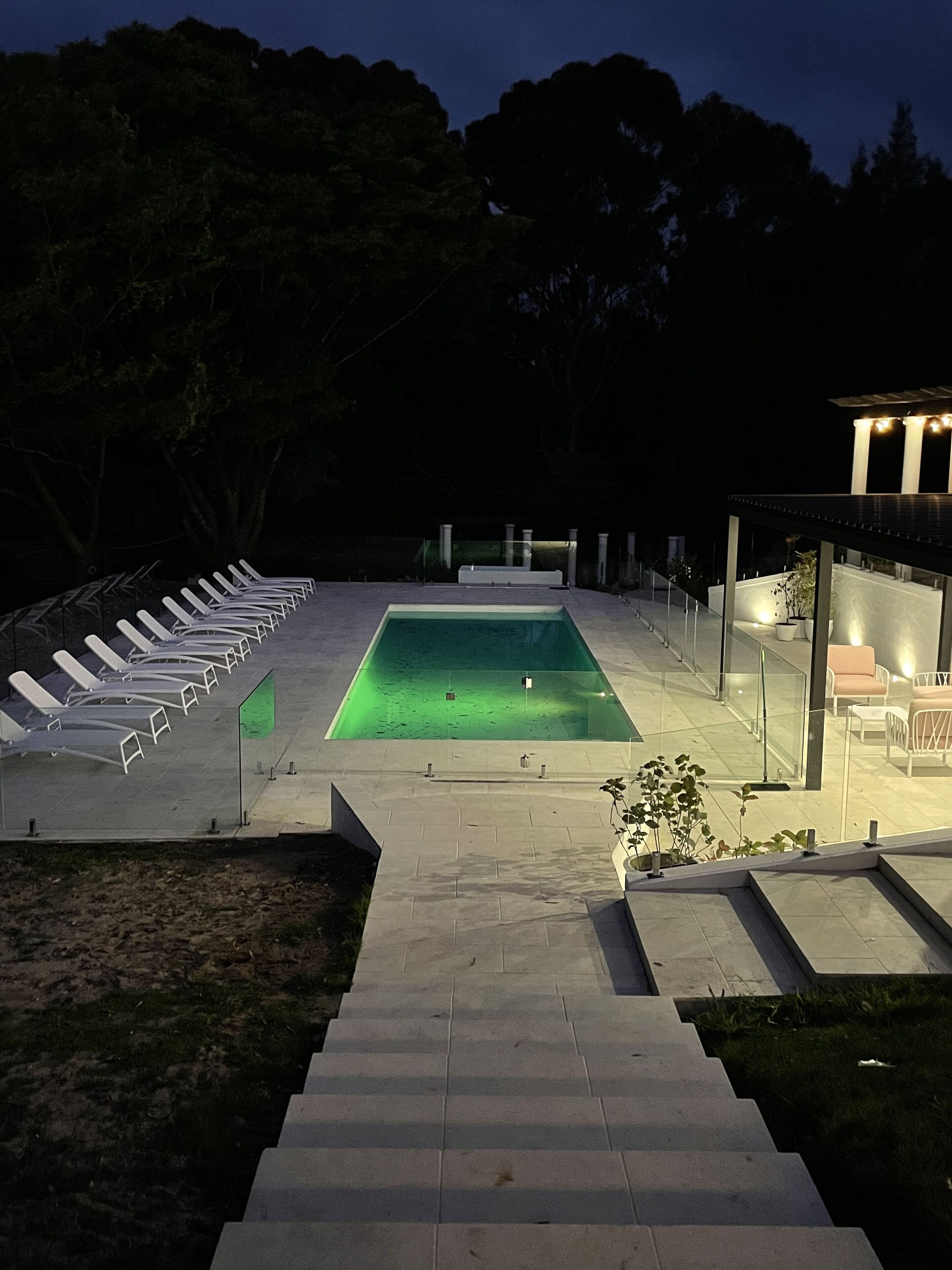 A swimming pool with a clear view of the water, surrounded by lounge chairs and a covered seating area.