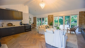 A spacious kitchen with dark cabinets, a herringbone floor, and a large window overlooking a garden. - Southern Highlands Finest! (Exeter)