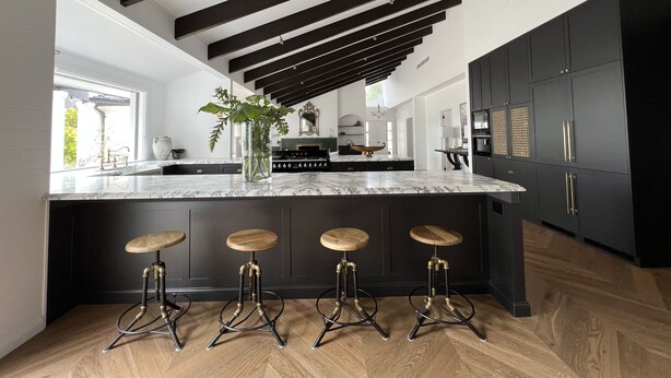 A modern kitchen with a marble island, dark cabinetry, and a wooden bar stool seating area. - Southern Highlands Finest! (Exeter)