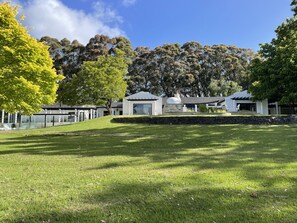 A modern house with a stone wall, a glass conservatory, and a well-maintained lawn. - Southern Highlands Finest! (Exeter)