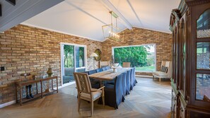 A dining area with a brick wall, wooden table, and chairs. - Southern Highlands Finest! (Exeter)
