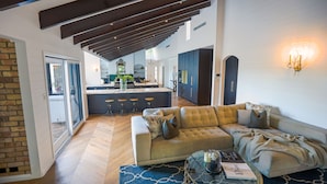 A spacious living area with a sofa, a glass coffee table, and a kitchen in the background. - Southern Highlands Finest! (Exeter)